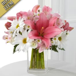 Pink lilies and white daisies arranged in a clear glass vase