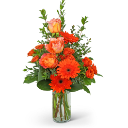 Orange roses and gerbera daisies in a clear glass vase