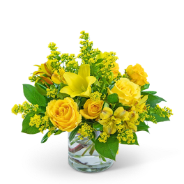 Yellow roses and lilies arranged in a clear glass vase
