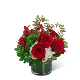 Red roses and white flowers in a glass vase with gold foliage