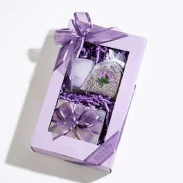 Lavender-themed gift box with candle, sachet, and small wrapped items tied with purple ribbon