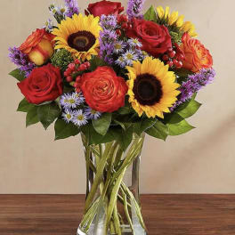 Bouquet of red roses and sunflowers in a clear glass vase
