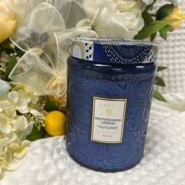 Blue candle jar beside a white floral arrangement with yellow lemons