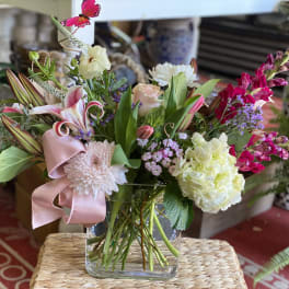 Mixed bouquet in a clear glass vase with pink ribbon and lilies
