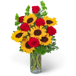 Bouquet of red roses and yellow sunflowers in a clear glass vase