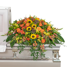 Large orange and yellow floral casket spray on a silver casket