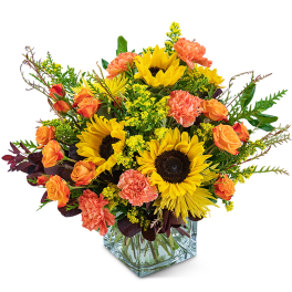 Sunflower and orange carnation bouquet in a clear glass vase