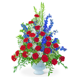 Red roses, red carnations, and blue delphinium in a white vase