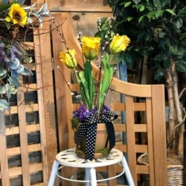 Yellow flowers in a small container tied with a black polka-dot ribbon