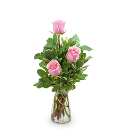 Pink roses arranged in a clear glass vase with variegated greenery
