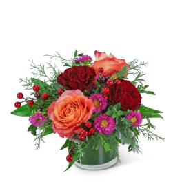 Arrangement of red and peach roses with purple daisies in a vase