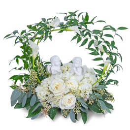 White roses and calla lilies in a circular floral wreath with angel figurines