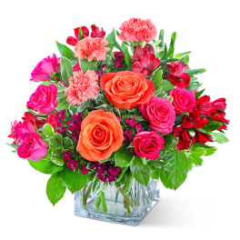 Mixed pink and orange flowers in a clear glass vase