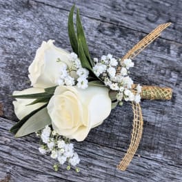 White rose boutonniere with baby's breath and gold ribbon on wood