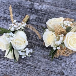 Two white rose corsages with baby's breath and gold ribbon accents