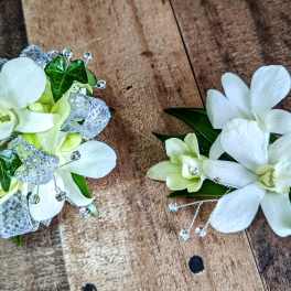 Two white orchid corsages with silver ribbon and bead accents