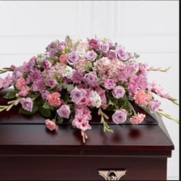 Pink and lavender floral spray on a dark casket