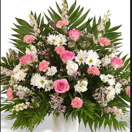 Pink roses and white daisies in a white vase with palm leaves