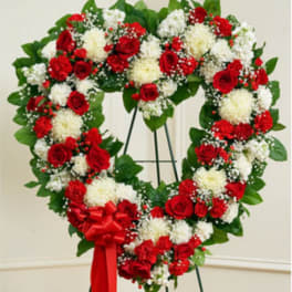Heart-shaped floral wreath of red and white flowers with a red ribbon