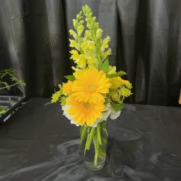 Yellow gerberas and snapdragons in a clear glass vase