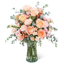 Peach and pink roses with carnations in a clear glass vase