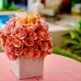 Peach and pink rose bouquet in a white square vase