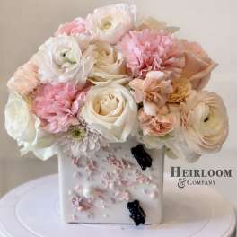 Pink and white bouquet in a decorated square vase