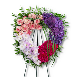 Heart-shaped floral wreath with pink roses, purple hydrangeas, white flowers, and magenta carnations