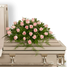 Pink rose casket spray with greenery on a silver casket