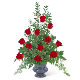 Red roses arranged in a clear glass vase with greenery