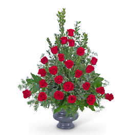 Red roses arranged in a gray vase with greenery