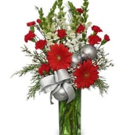 Tall red and white flower arrangement with silver ornaments in a green glass vase