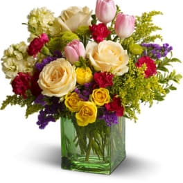 Mixed bouquet of roses, tulips, and carnations in a green glass vase