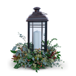 Black lantern with a white candle and greenery base