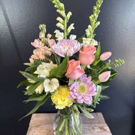 Mixed bouquet in a glass vase with pink roses, lilies, and pastel blooms