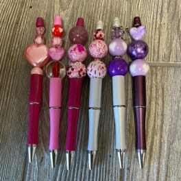Decorative pens with beaded heart and glitter toppers in pink and purple.