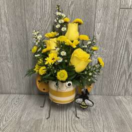 Yellow rose and daisy arrangement in a bee-themed pot with a bee charm