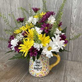 Bouquet of yellow, white, and purple daisies in a floral mug