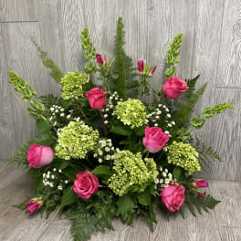 Pink roses and green hydrangeas arranged with tall greenery.