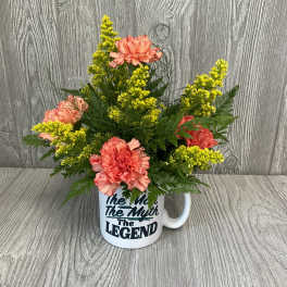 Pink carnations and yellow filler flowers in a white mug