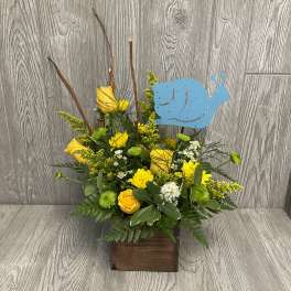 Yellow roses and daisies in a wooden box with a blue snail pick