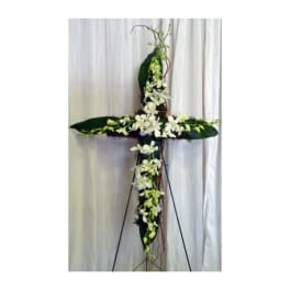 White floral cross-shaped standing arrangement on an easel