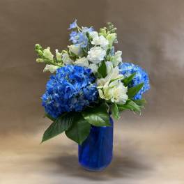 Blue and white flower arrangement in a cobalt glass vase