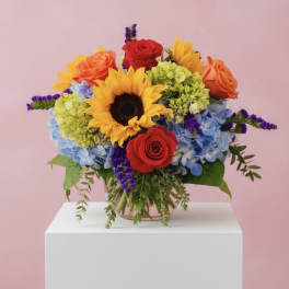 Colorful bouquet with sunflowers, roses, and hydrangeas in a glass vase