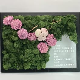 Framed moss wall with pink flowers and a quote panel