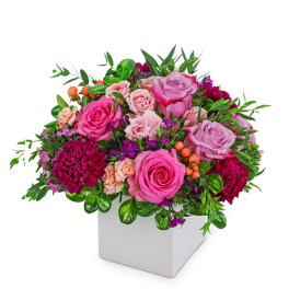 Pink and lavender roses with carnations in a white square vase