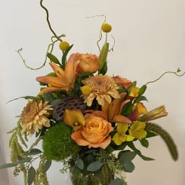 Orange and yellow floral arrangement in a clear glass vase