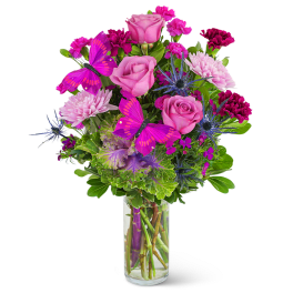Pink roses and magenta flowers in a clear glass vase with purple butterflies