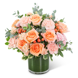 Peach roses and pink carnations in a glass vase