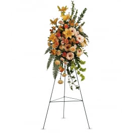Tall standing spray of yellow lilies and peach flowers arranged on a metal easel
